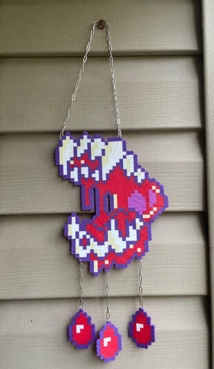a perler in the shape of a canines mouth with blood drips hanging from it with chains