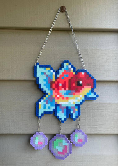 a perler in the shape of a fish with bubbles hanging from it hanging on a nail